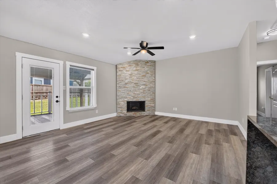 Living room with a stacked stone fireplace and a glass door to the rear deck at 716 River Hill Ln