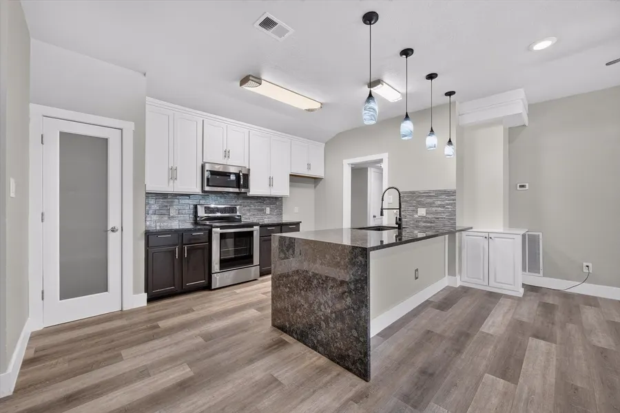 Kitchen with a stone topped peninsula, stainless range, and white upper cabinets at 716 River Hill Ln